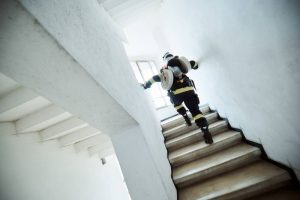 Pompier în echipament complet urcând scările într-o clădire.