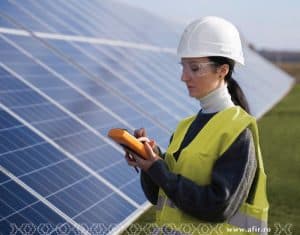 Ingineră verificând panouri solare cu dispozitiv de măsurare.