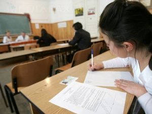 Elevă scriind la examen în sala de clasă, în Bacău.
