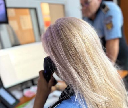 Femeie cu părul blond vorbind la telefon în birou.