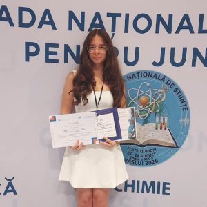 Tânără premiantă la concursul național de științe pe scenă, ținând diplome.