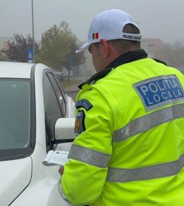 Atenție unde parcați în Bacău: Poliția a aplicat zeci de amenzi și cere datele a 79 de proprietari de mașini 2 Ofițer de poliție locală verificând documente lângă mașina de patrulă.