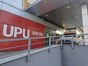Ambulanță la intrarea în UPU Bacău lângă fațada roșie.