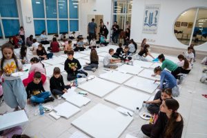 Copii desenând pe pânze albe în atelier de creație.