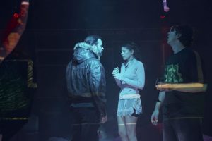 Actori în scenă într-un spectacol teatral în backstage, lumini difuze albastre.