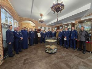 Echipaj militar într-un muzeu, în jurul unei vitrine cu artefacte, încadrați într-un spațiu istoric.