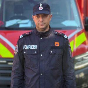 Pompier din Bacău în uniformă, în fața unei autospeciale de intervenție.