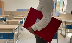 Elev cu dosar roșu în clasă, pregătit pentru școală.