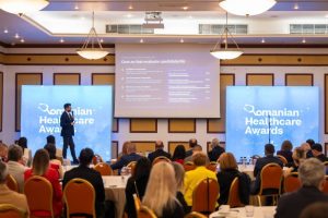 Performanță incredibilă la Buhuși: spitalul propus pentru desființare a cucerit trei premii de excelență la Romanian Healthcare Awards 5 Eveniment costumat la Romanian Healthcare Awards, prezentator pe scenă, audiență atentă în sală.